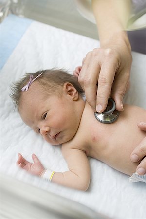 Vue d'angle élevé des mains du médecin examinant un nouveau-né avec un stéthoscope Photographie de stock - Premium Libres de Droits, Code: 640-01363227