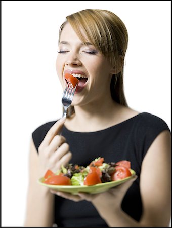 Close-up of a young woman eating a slice of tomato Stock Photo - Premium Royalty-Free, Code: 640-01363249