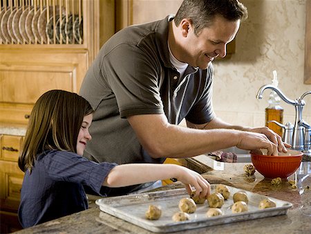 simsearch:640-01357998,k - Girl in kitchen with man baking cookies Stock Photo - Premium Royalty-Free, Code: 640-01363462
