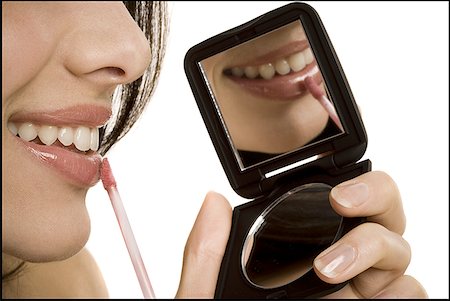 Closeup of woman applying lipstick with compact mirror Stock Photo - Premium Royalty-Free, Code: 640-01363544