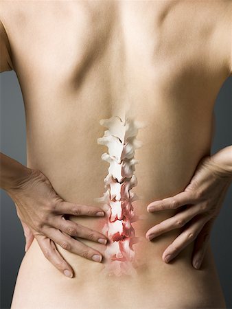 Rear view of woman with hands on back and sore spine Stock Photo - Premium Royalty-Free, Code: 640-01458435