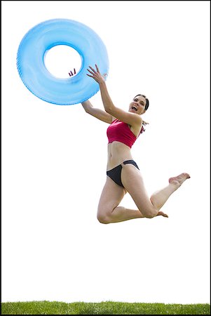 Woman in bikini jumping and smiling with swimming ring Stock Photo - Premium Royalty-Free, Code: 640-01458442