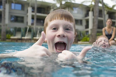 Boy in outdoor pool making funny face with thumbs up Foto de stock - Sin royalties Premium, Código: 640-01458642