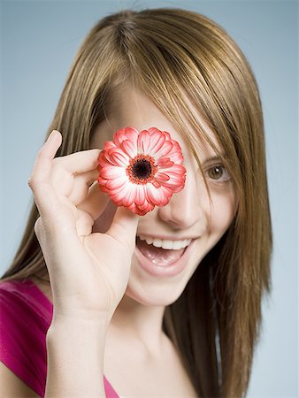 simsearch:640-02773811,k - Close-up of woman smiling holding flower up to her eye Stock Photo - Premium Royalty-Free, Code: 640-01458744