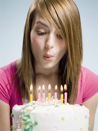 Woman blowing out candles on a birthday cake Stock Photo - Premium Royalty-Free, Code: 640-01458745