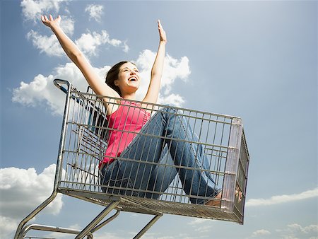 simsearch:640-02773934,k - Woman in shopping cart outdoors with arms up smiling Foto de stock - Royalty Free Premium, Número: 640-01458851