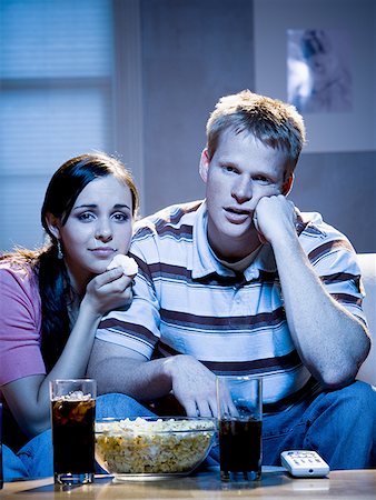 Couple watching television with bowl of popcorn and tissue looking sad Stock Photo - Premium Royalty-Free, Code: 640-01458915