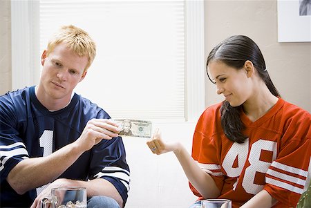 football fan on couch - Man and woman in football jerseys handing woman money Stock Photo - Premium Royalty-Free, Code: 640-01458929