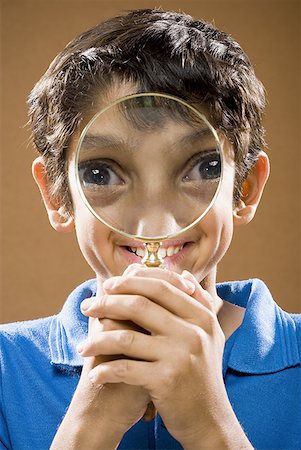 simsearch:640-02774651,k - Boy holding magnifying glass to face smiling Foto de stock - Sin royalties Premium, Código: 640-01575103