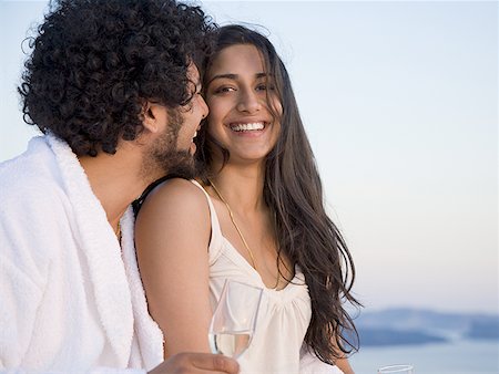 Couple sitting outdoors with champagne flutes and scenic background smiling and snuggling Stock Photo - Premium Royalty-Free, Code: 640-01575161