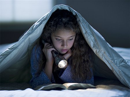 Fille pose dans son lit sous couverture avec lecture de lampe de poche Photographie de stock - Premium Libres de Droits, Code: 640-01601306