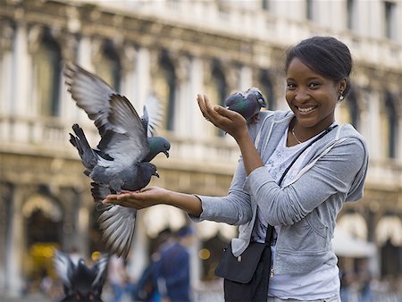 Woman in public square with pigeons smiling Stock Photo - Premium Royalty-Free, Code: 640-01601350