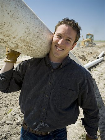 simsearch:640-01645400,k - Man carrying pipe outdoors smiling Stock Photo - Premium Royalty-Free, Code: 640-01601360