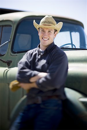 Man in cowboy hat leaning on truck smiling Stock Photo - Premium Royalty-Free, Code: 640-01601361
