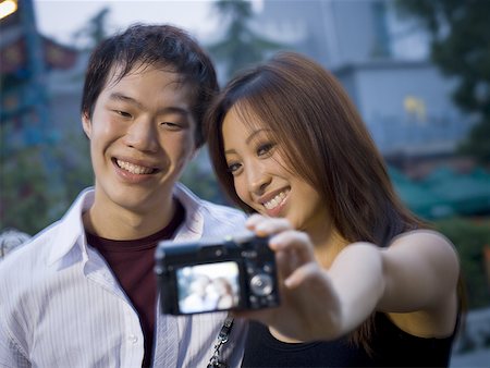 Couple embracing and smiling outdoors with camera Stock Photo - Premium Royalty-Free, Code: 640-01601399