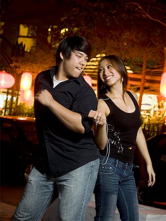 Couple listening to mp3 player outdoors dancing and smiling Stock Photo - Premium Royalty-Free, Code: 640-01601408