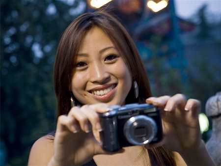 simsearch:640-01601405,k - Woman taking a photograph smiling Foto de stock - Royalty Free Premium, Número: 640-01601403