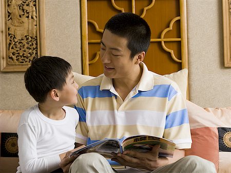 dad reads to children the book in the chair - Father and son reading magazine Stock Photo - Premium Royalty-Free, Code: 640-01601432