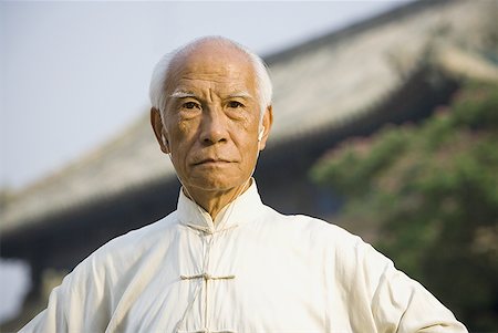 Man standing outdoors with ear buds and pagoda in background Stock Photo - Premium Royalty-Free, Code: 640-01601479