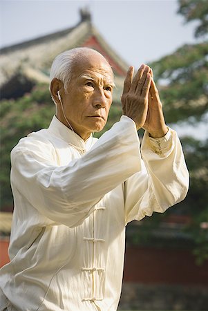 senior man introspective - Man standing outdoors doing Kung Fu with ear buds and pagoda in background Foto de stock - Sin royalties Premium, Código: 640-01601481