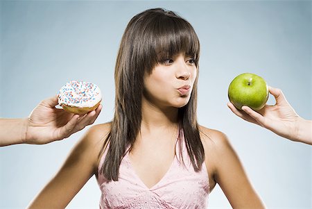 Woman deciding between a donut and green apple Stock Photo - Premium Royalty-Free, Code: 640-01601566