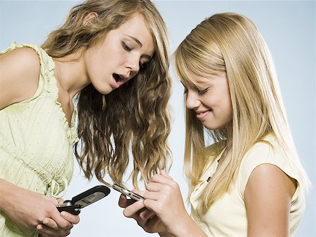 simsearch:640-01601405,k - Two girls with cell phones smiling Foto de stock - Royalty Free Premium, Número: 640-01601658