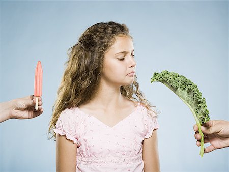 Girl deciding between Popsicle and green leafy vegetable Stock Photo - Premium Royalty-Free, Code: 640-01601681