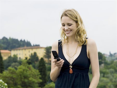 simsearch:640-01601762,k - Femme avec téléphone cellulaire souriant à l'extérieur Photographie de stock - Premium Libres de Droits, Code: 640-01601758