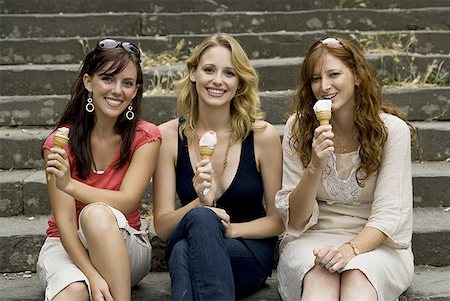 Three women sitting on steps outdoors eating ice cream cones smiling Stock Photo - Premium Royalty-Free, Code: 640-01601765