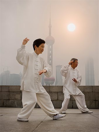 simsearch:640-02775784,k - Couple faisant tai chi en plein air avec des toits de la ville en arrière-plan Photographie de stock - Premium Libres de Droits, Code: 640-01645296