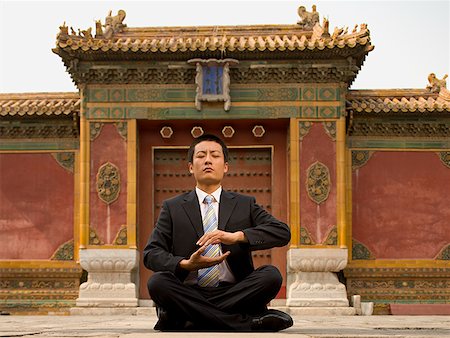 Businessman sitting cross legged outdoors meditating Stock Photo - Premium Royalty-Free, Code: 640-01645354