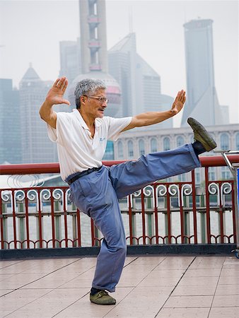 Man doing tai chi outdoors with city skyline in background Stock Photo - Premium Royalty-Free, Code: 640-01645440