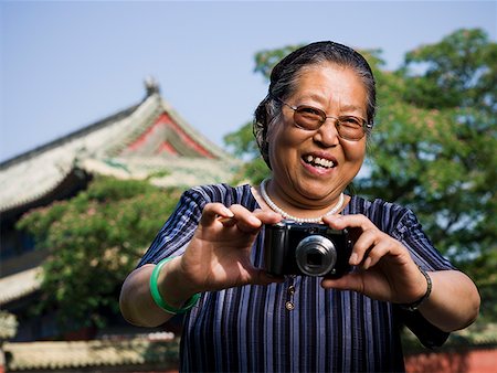 Mature woman with camera outdoors smiling Stock Photo - Premium Royalty-Free, Code: 640-01645471