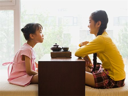 Profile of two girls sitting cross legged having tea Fotografie stock - Premium Royalty-Free, Codice: 640-01645480