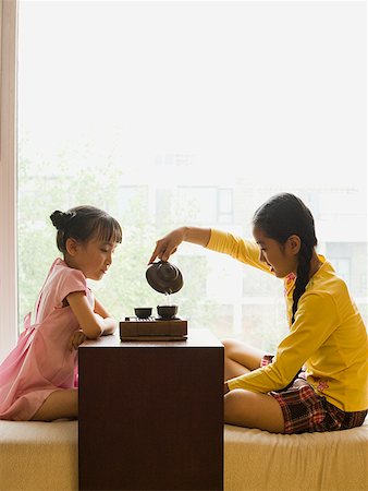 Profile of two girls sitting cross legged having tea Fotografie stock - Premium Royalty-Free, Codice: 640-01645481