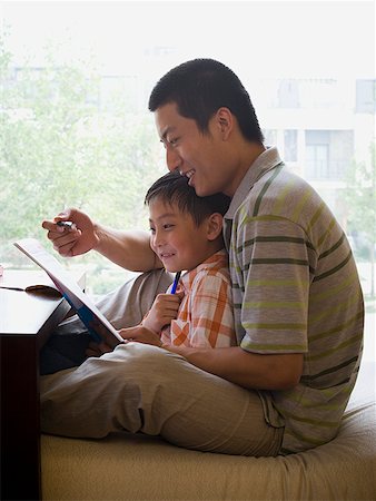 Man and boy sitting and reading in front of large window Stock Photo - Premium Royalty-Free, Code: 640-01645514