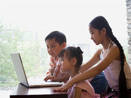 Three children sitting in front of large window with laptop Fotografie stock - Premium Royalty-Free, Codice: 640-01645519
