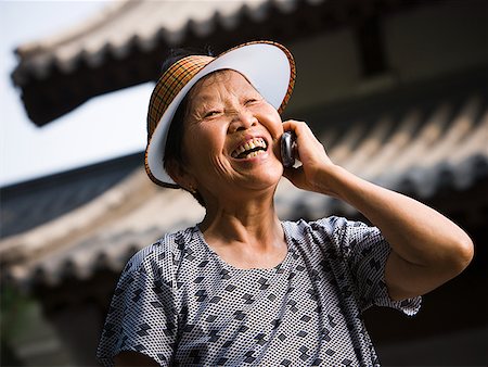 simsearch:640-01601405,k - Woman with sun visor outdoors smiling talking on cell phone Foto de stock - Royalty Free Premium, Número: 640-01645566