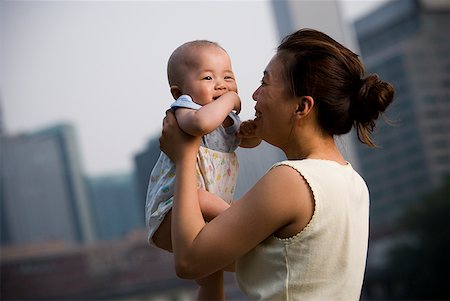 simsearch:640-01458949,k - Femme tenant un bébé souriant de plein air Photographie de stock - Premium Libres de Droits, Code: 640-01645580