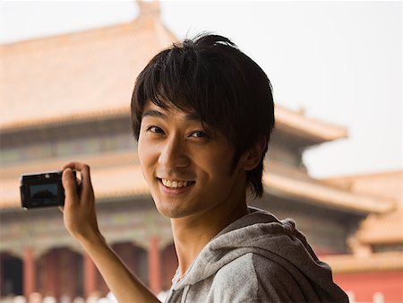 Teenage boy outdoors with digital camera smiling Stock Photo - Premium Royalty-Free, Code: 640-01645617