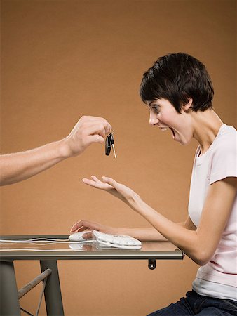 Woman sitting at computer with hand emerging from monitor holding car keys Stock Photo - Premium Royalty-Free, Code: 640-01645768