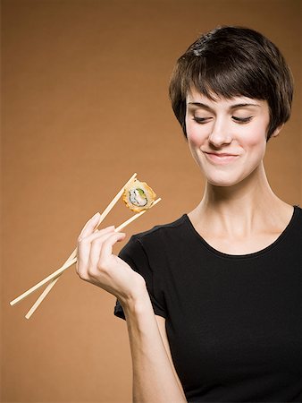 simsearch:640-01645781,k - Woman holding sushi with chopsticks smiling Stock Photo - Premium Royalty-Free, Code: 640-01645786