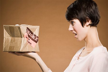 Woman holding crushed cardboard box with fragile label Stock Photo - Premium Royalty-Free, Code: 640-01645794