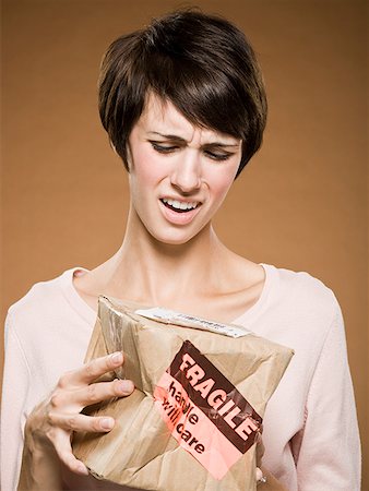 Woman holding crushed cardboard box with fragile label Stock Photo - Premium Royalty-Free, Code: 640-01645792