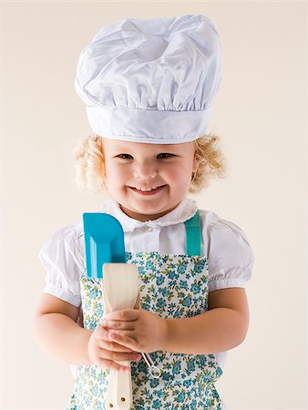 Little girl wearing a chef's hat and holding spoons. Stock Photo - Premium Royalty-Free, Code: 640-02655767