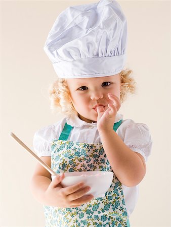 Little girl wearing a chef's hat and holding a bowl. Stock Photo - Premium Royalty-Free, Code: 640-02655768