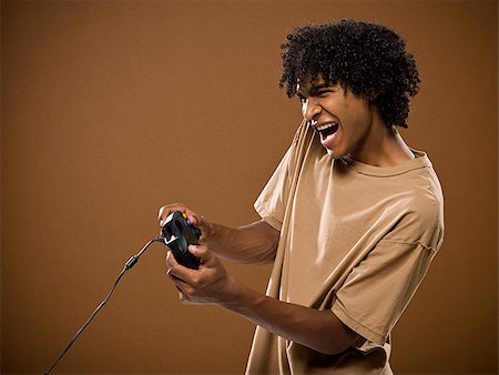 jeune homme dans une chemise brune jouant à un jeu vidéo. Photographie de stock - Premium Libres de Droits, Code: 640-02656864