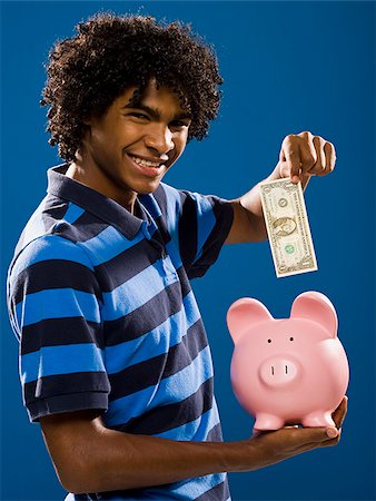 young man putting money in a piggy bank. Stock Photo - Premium Royalty-Free, Code: 640-02656898