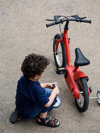 rodinha da bicicleta - boy fixing his bike Foto de stock - Royalty Free Premium, Número: 640-02657875