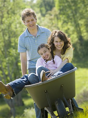 Man pushing his daughter and his wife in a wheelbarrow Stock Photo - Premium Royalty-Free, Code: 640-02764647